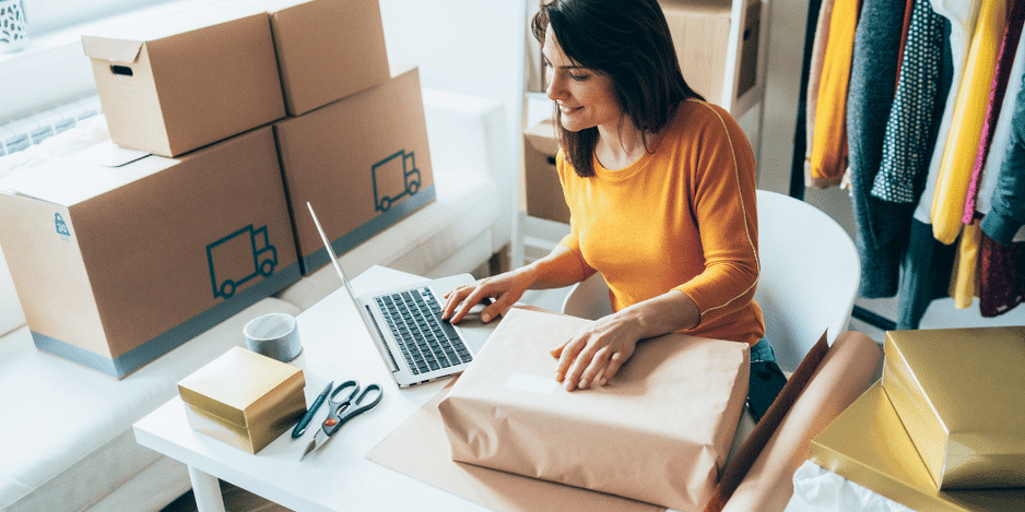 business owner working on her laptop while she packs an order